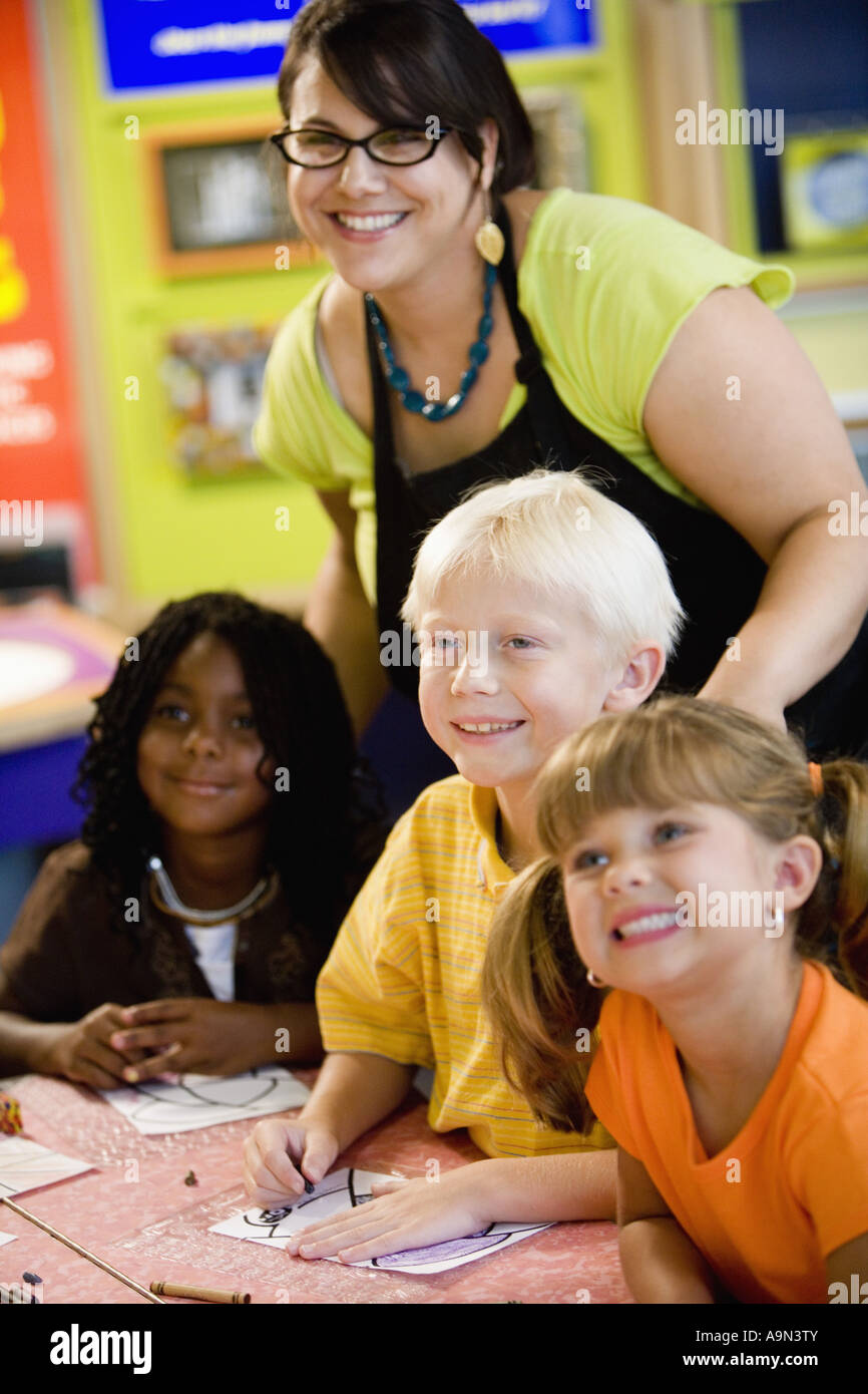 Kids posing and smiling with their teacher in a colorful classroom ...