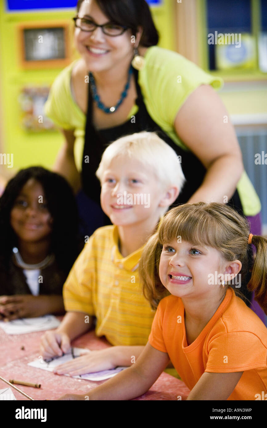 Kids posing and smiling with their teacher in a colorful classroom ...