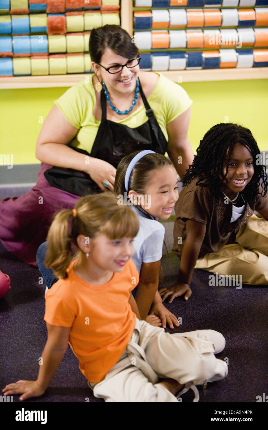 Teacher sitting and posing with students in a colorful classroom Stock ...