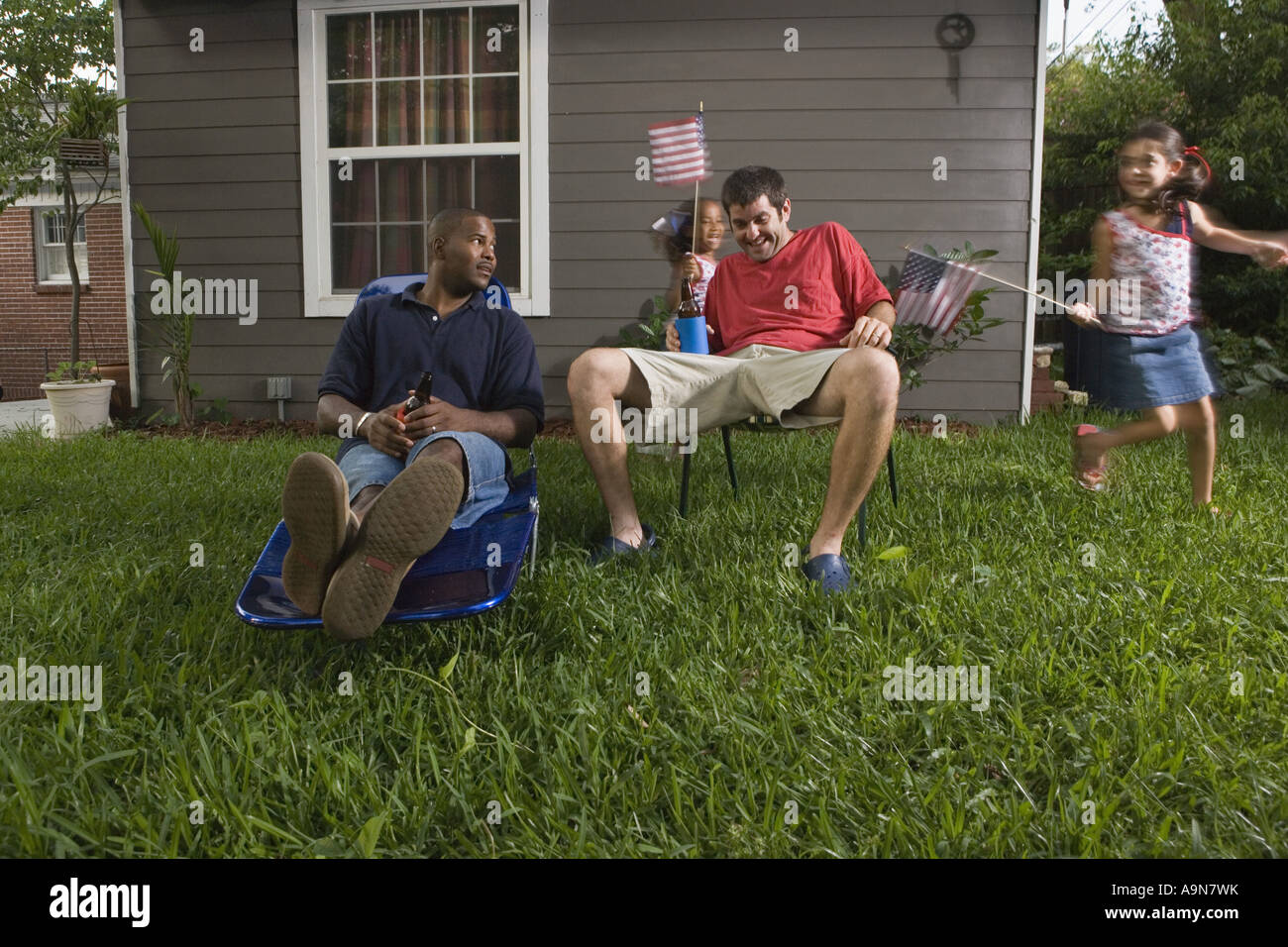 Two young men sitting on lawn chairs enjoying a beer while daughters