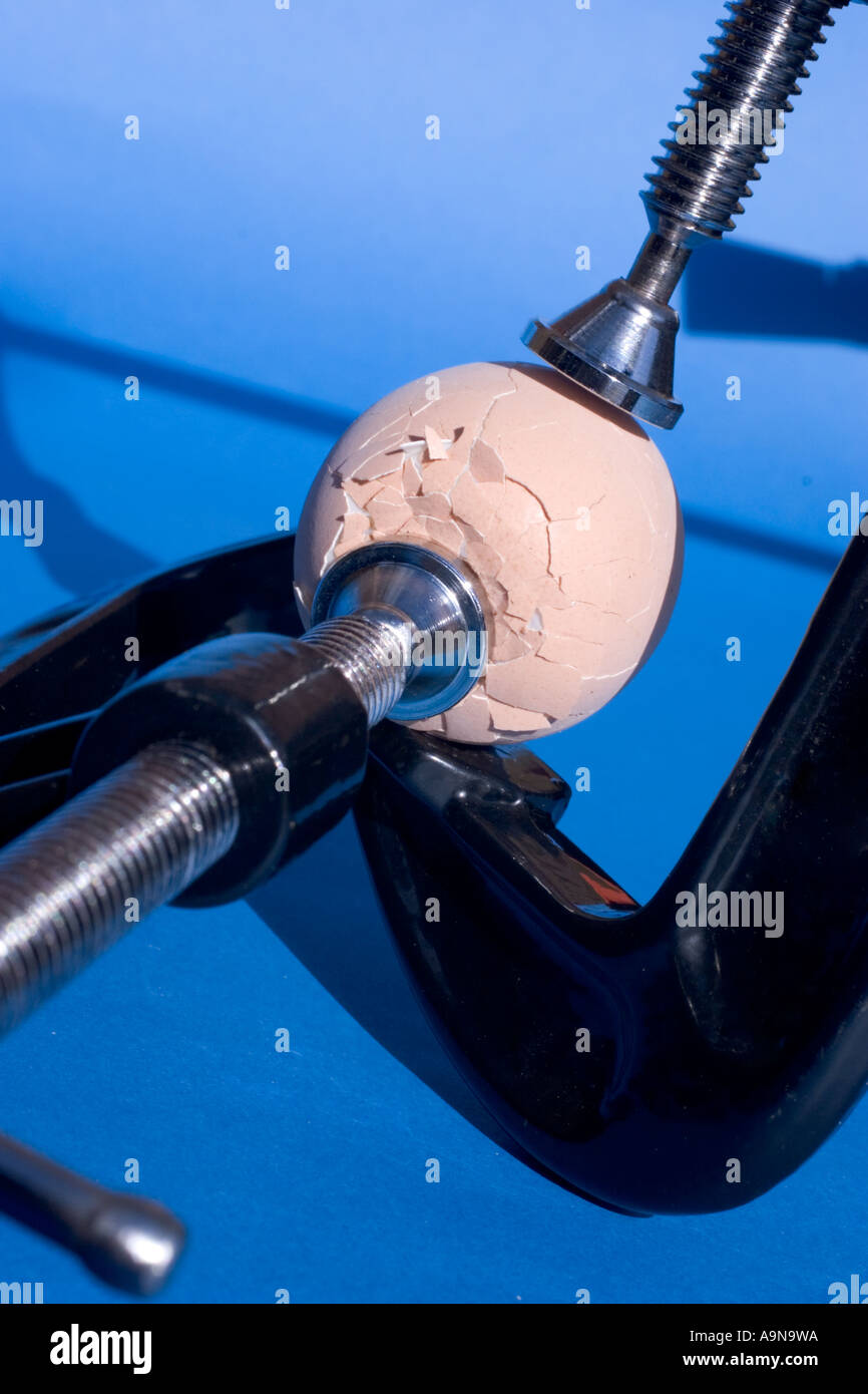 Pressure crush broken egg being crushed with clamps Stock Photo Alamy