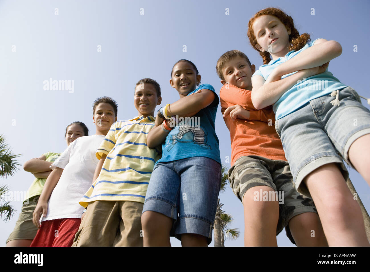 Portrait of children with folded arms standing abreast at a