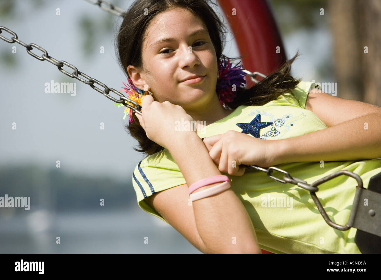 Portrait of a smiling girl on a swing at a playground Stock Photo - Alamy