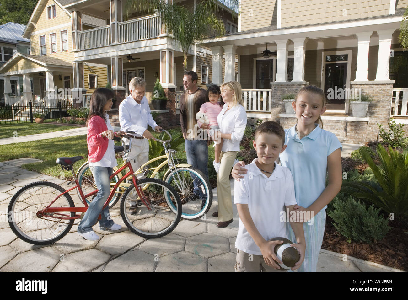 Family with young children conversing with neighbors in front of house Stock Photo