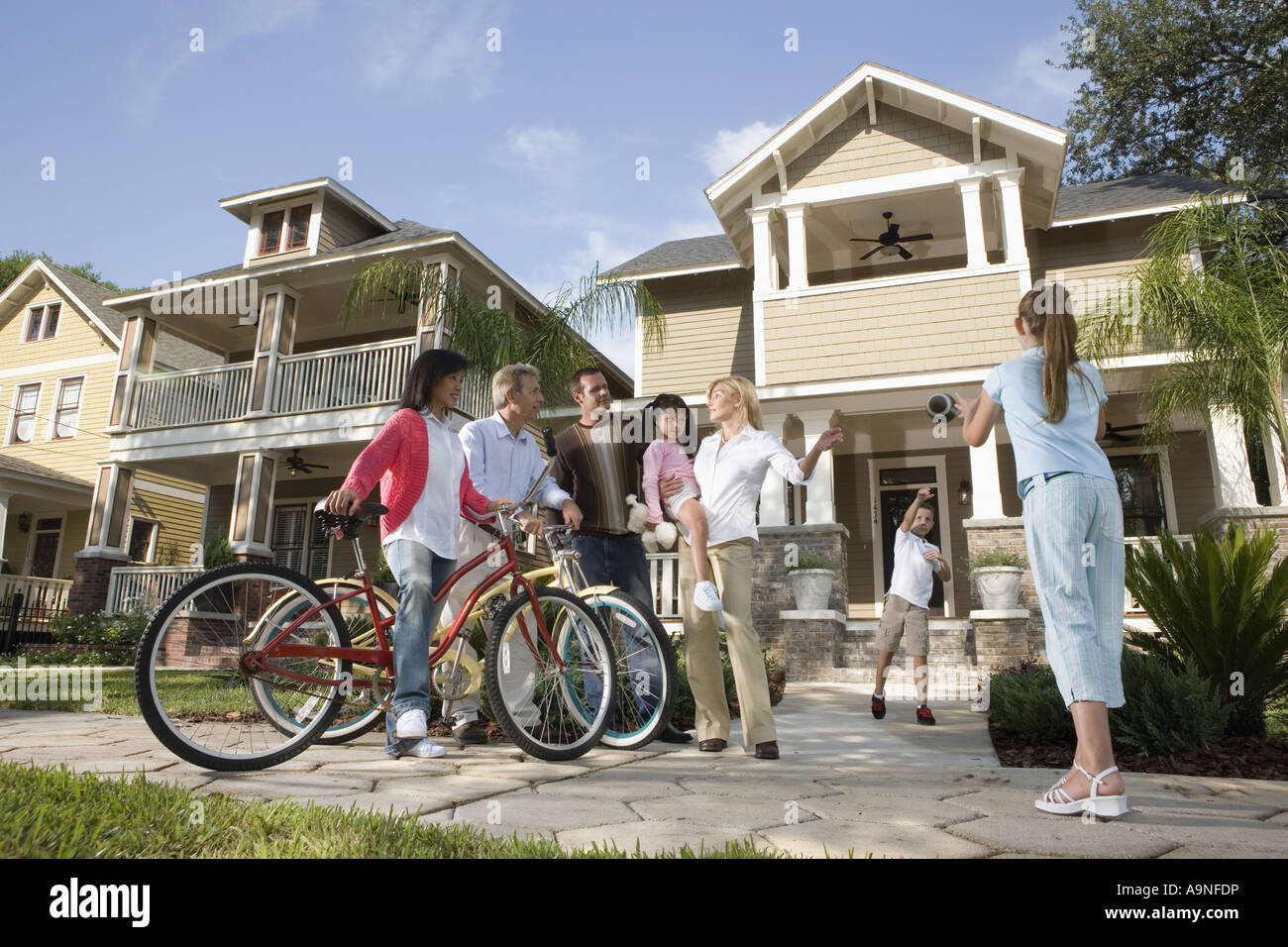Family with young children conversing with neighbors in front of house Stock Photo