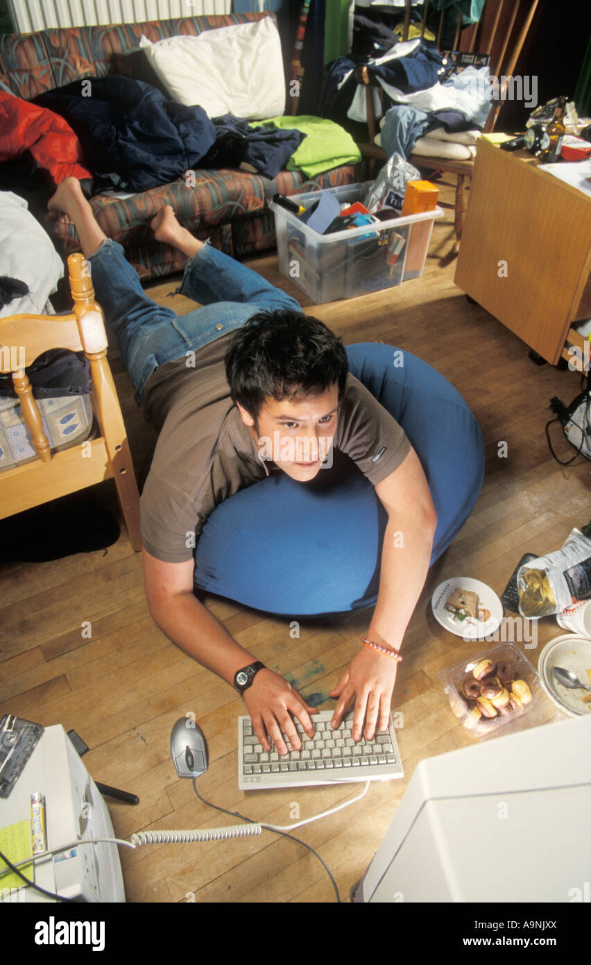 teenage boy computer nerd playing on his computer in his messy room