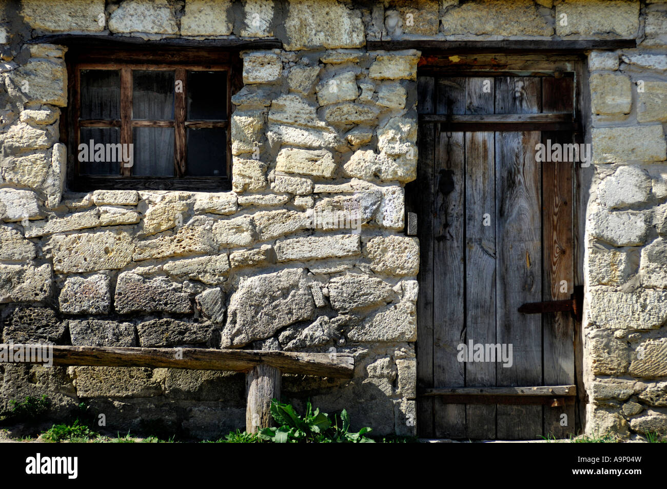 Ancient old stone house wall with an old wooden door and a window Stock ...