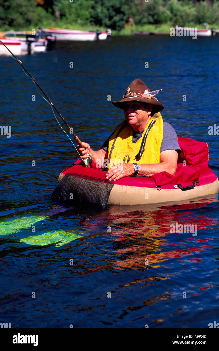 Fly Fisherman in a Belly Boat fishing for Trout in Hi Hium Lake in the Cariboo Region of British Columbia Canada Stock Photo
