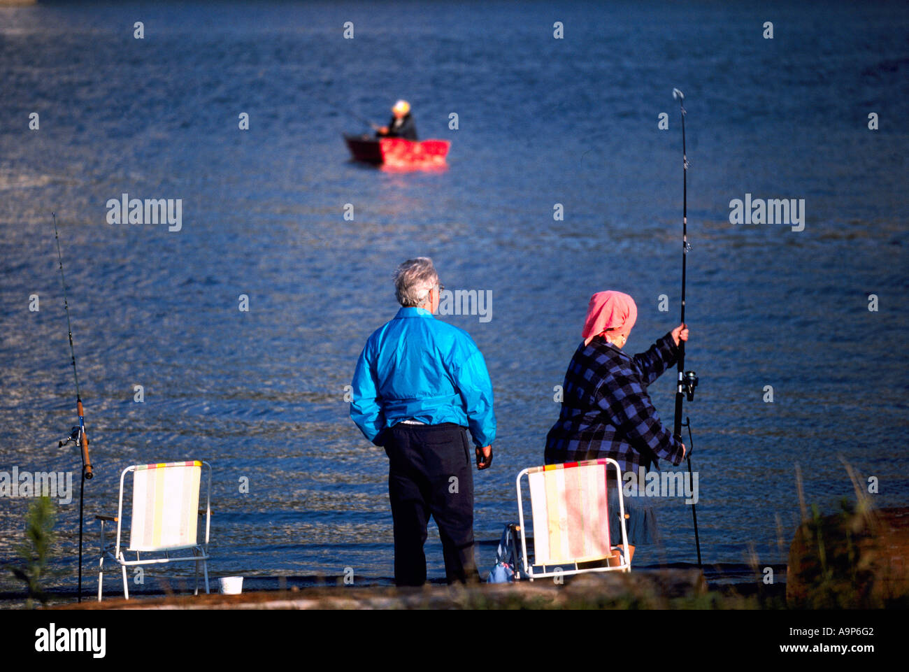 Couple fishing from Shore in Fraser River, New Westminster, BC, British Columbia, Canada - Fisherman fishes from Rowboat Stock Photo