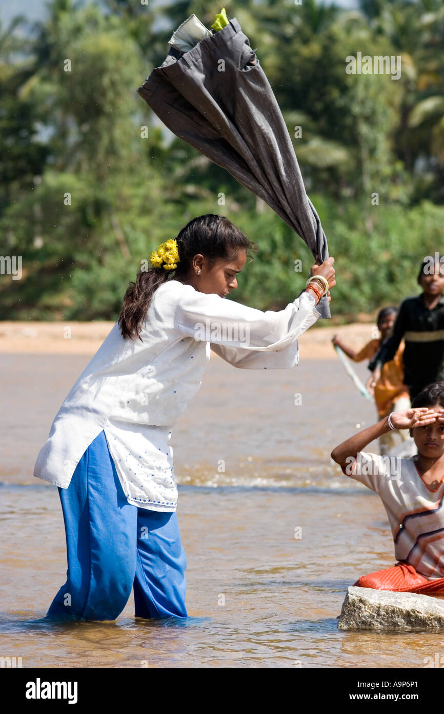 Indian laundry girl (dhobi) beating the water out of  clothes after washing in the river. Andhra Pradesh, India Stock Photo