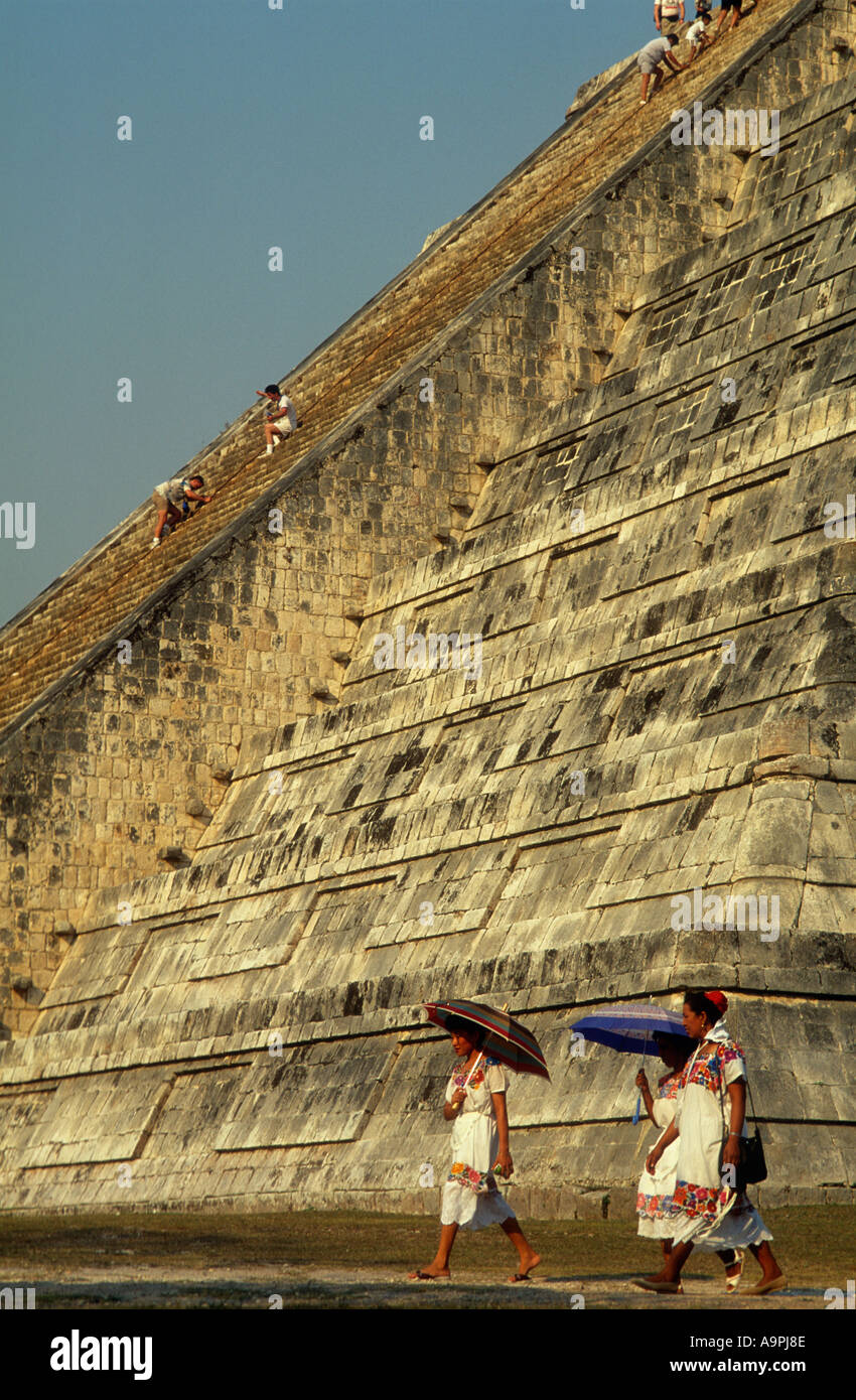 Mexico Yucatan State Chichen Itza El Castillo Mayan women walking past pyramid Stock Photo
