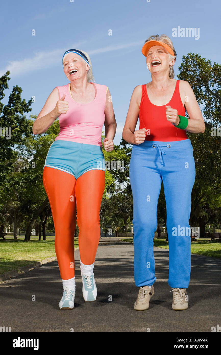 Two mature adult women running in park Stock Photo