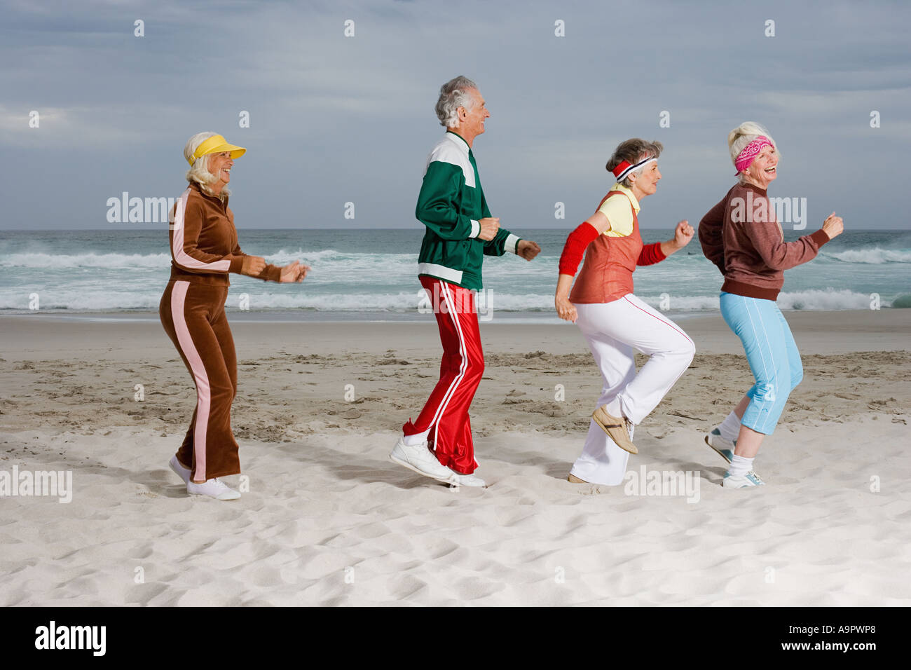 Four senior adult running on the beach Stock Photo