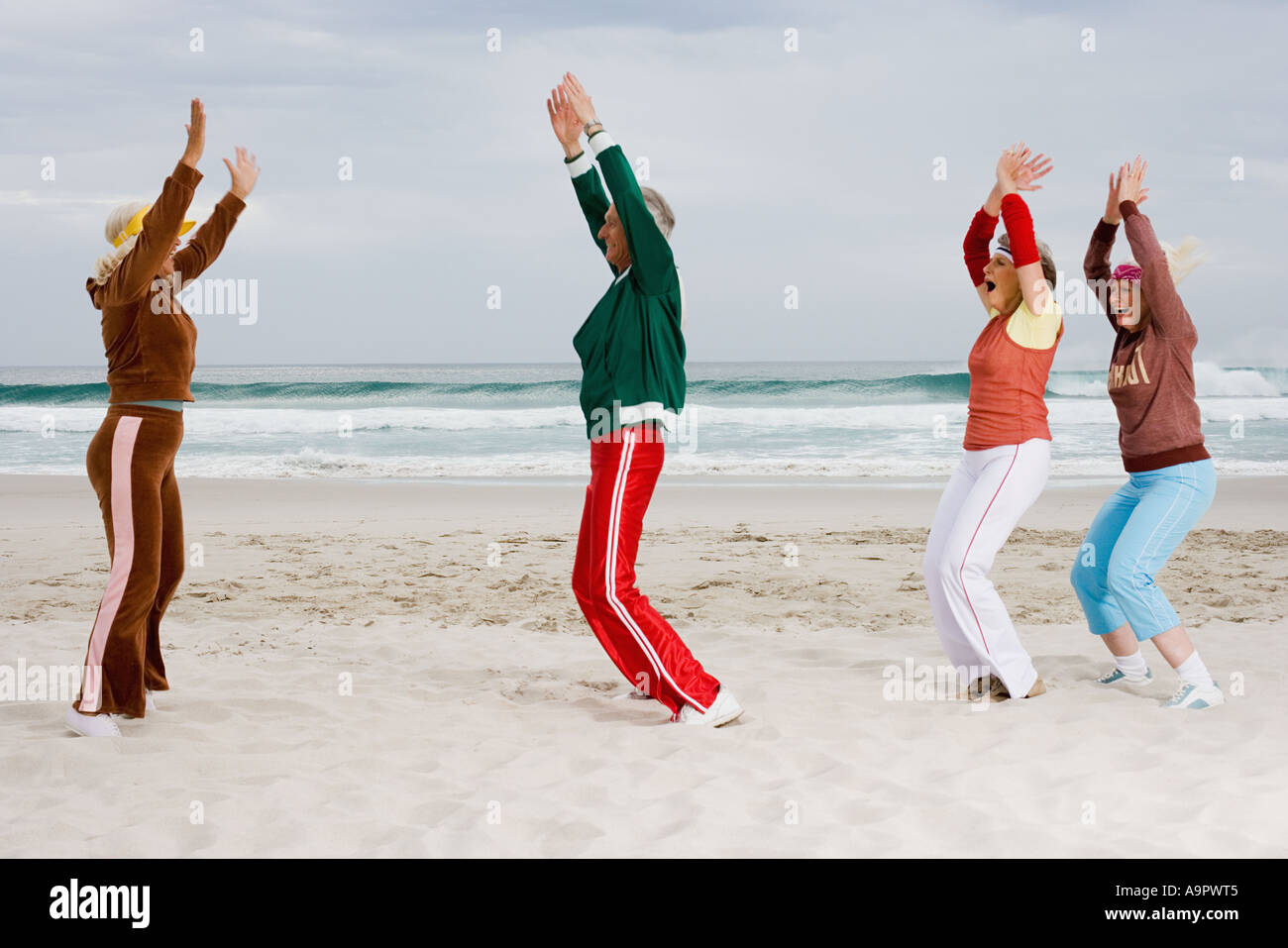 Four senior adults exercising on the beach Stock Photo