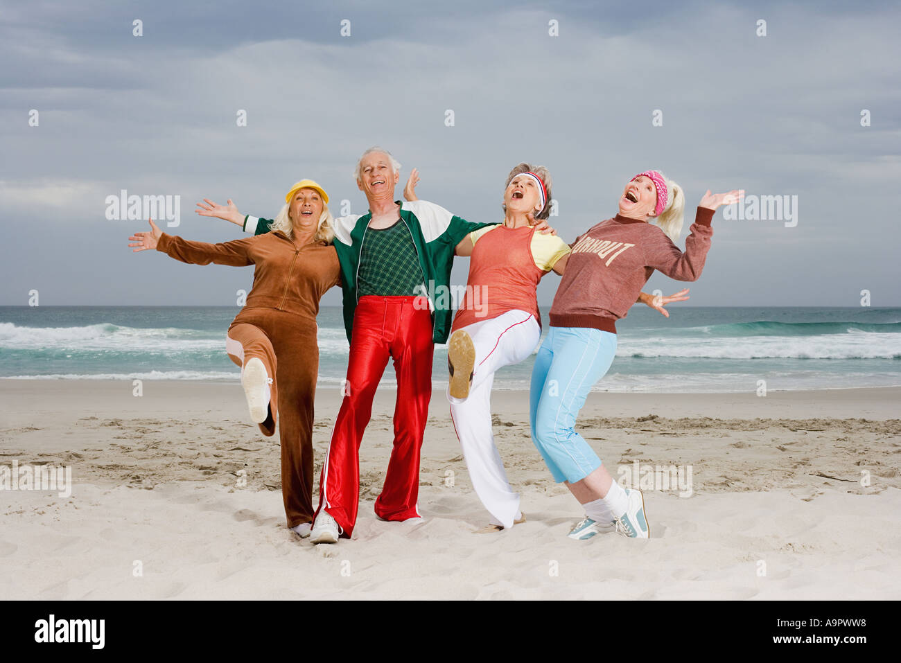 Four senior adults exercising on beach Stock Photo