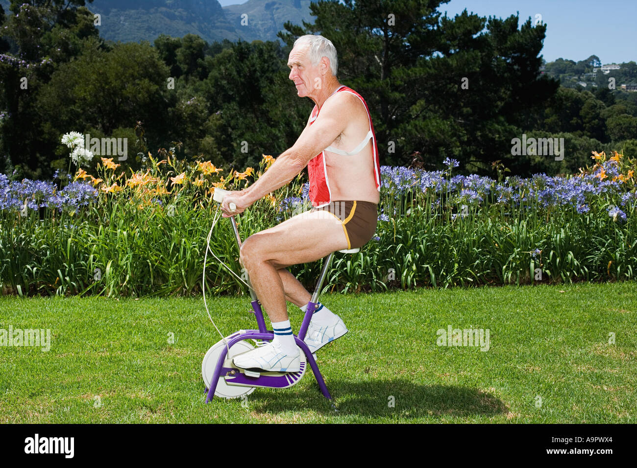 Senior adult man riding exercise bike Stock Photo
