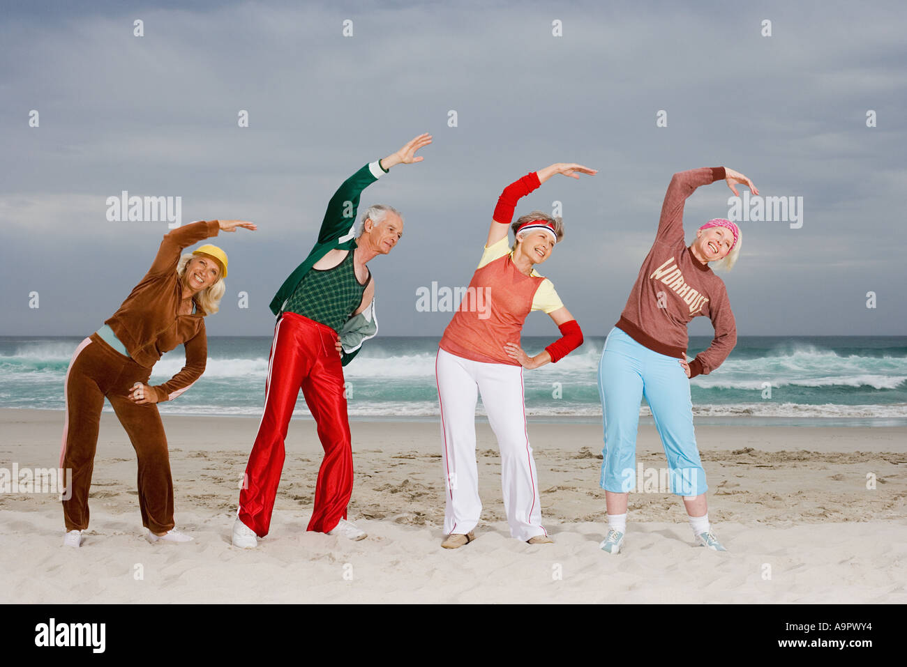 Four senior adults stretching on beach Stock Photo