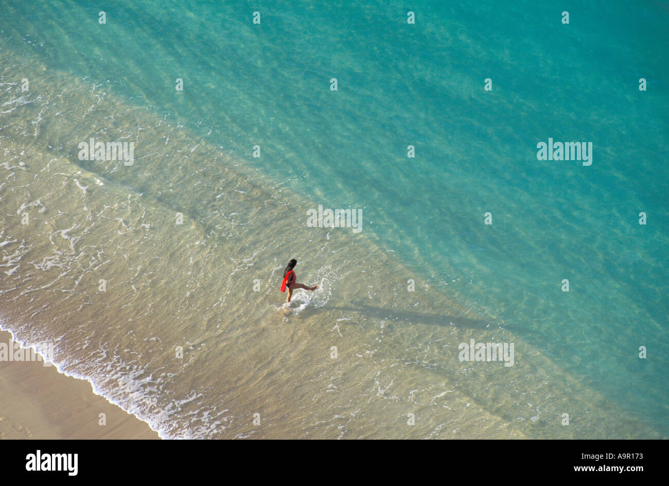 Woman walking into clear shoreline waters along Waikiki Beach on Oahu Island in Hawaii at sunrise Stock Photo