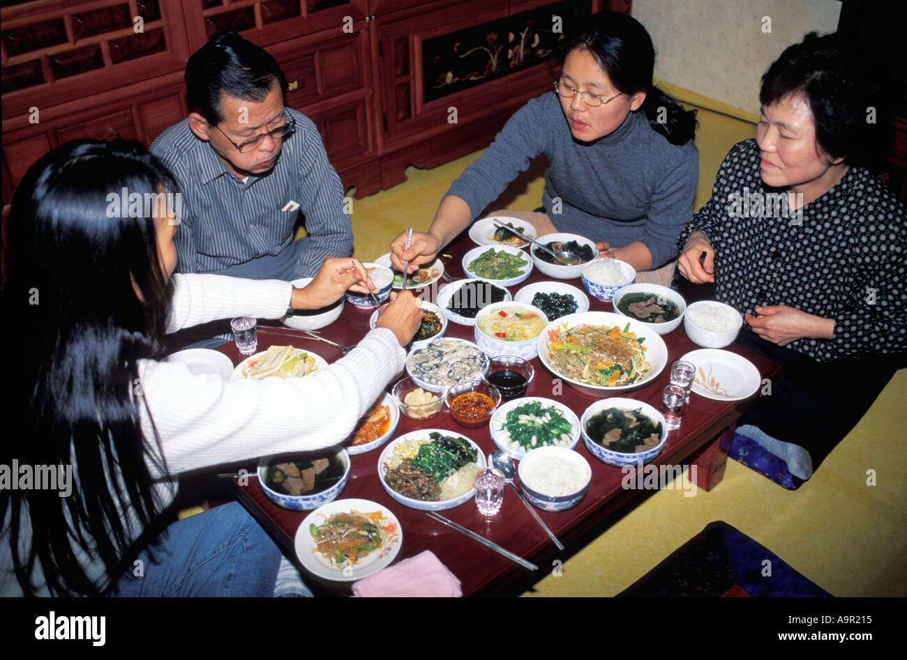 korean-family-eating-traditional-food-in-typical-home-setting-stock