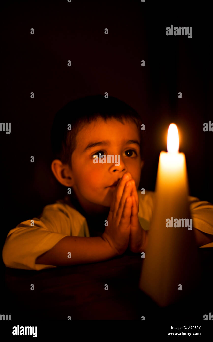 Boy prays by candlelight Stock Photo
