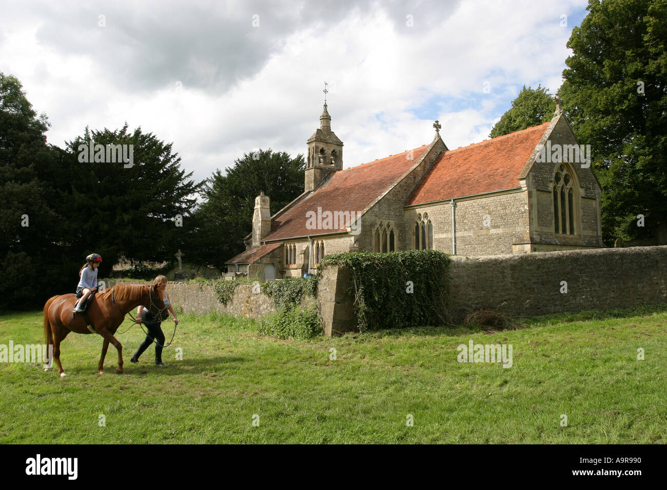 Horse and rider being led past an ancient church Stock Photo