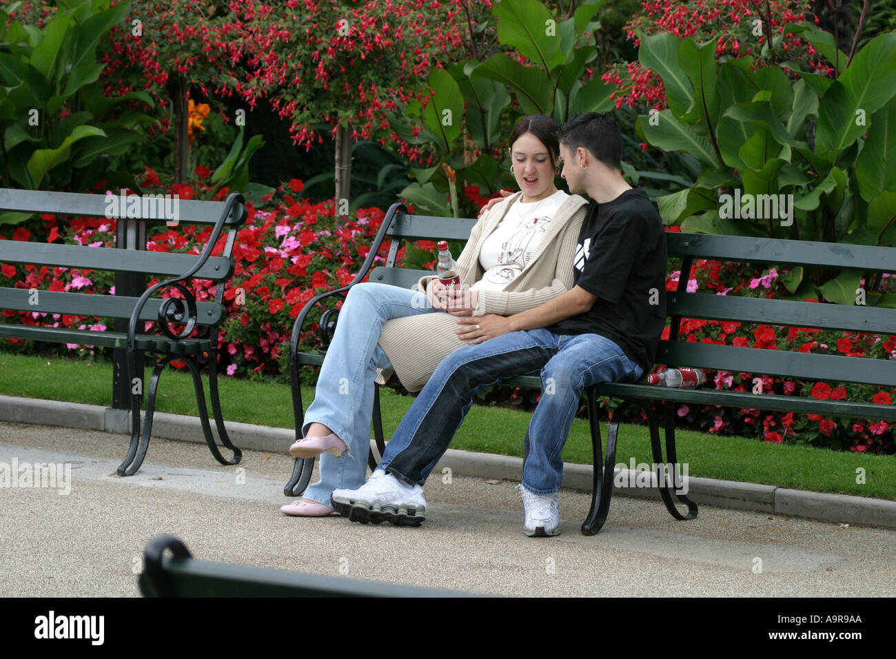 A young couple together on a park bench Stock Photo - Alamy