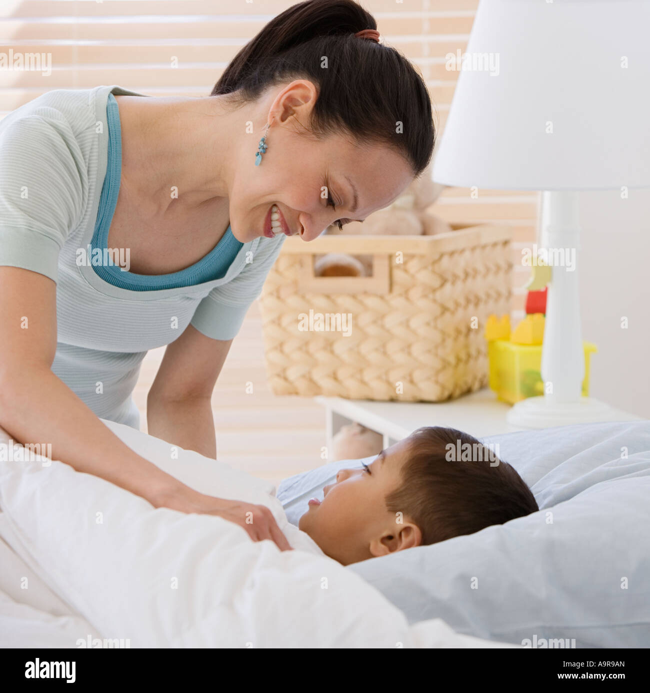 Asian mother tucking son into bed Stock Photo Alamy