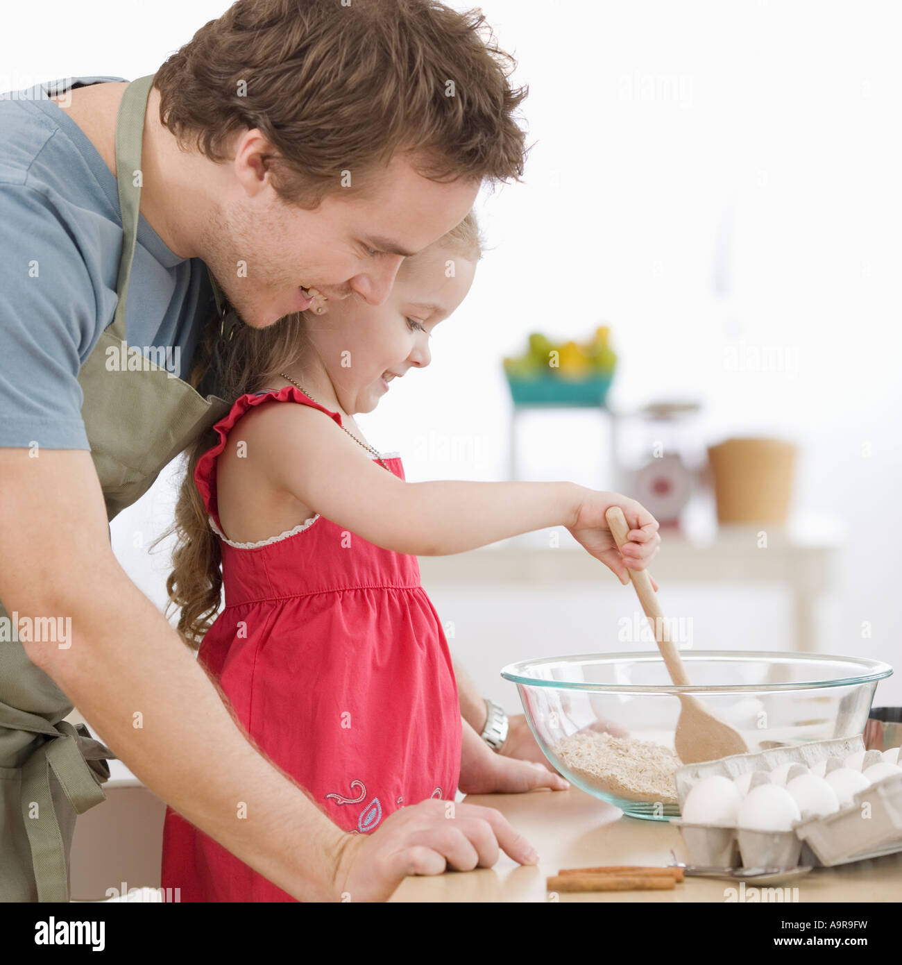 Father and daughter mixing batter in kitchen Stock Photo