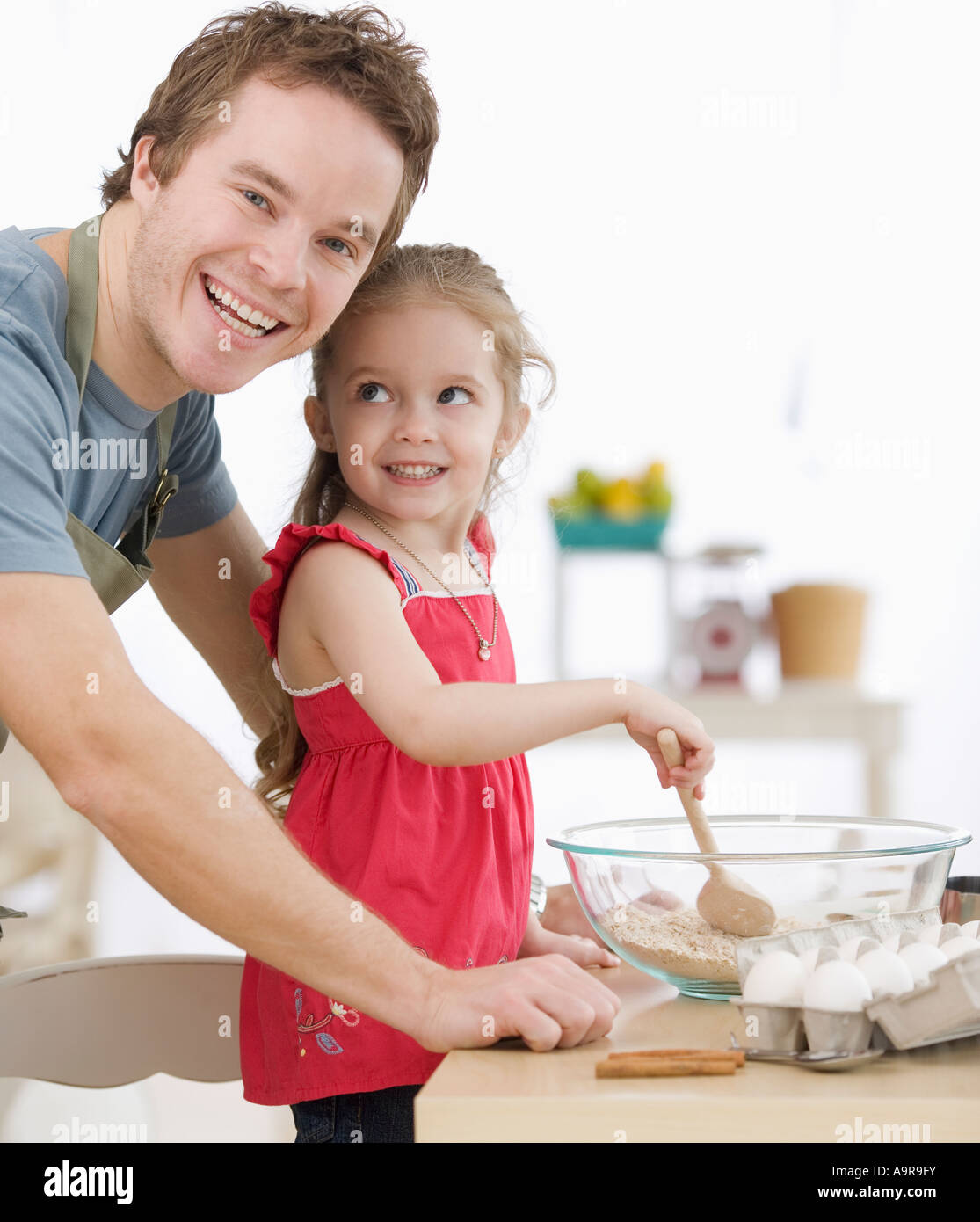 Father and daughter mixing batter in kitchen Stock Photo