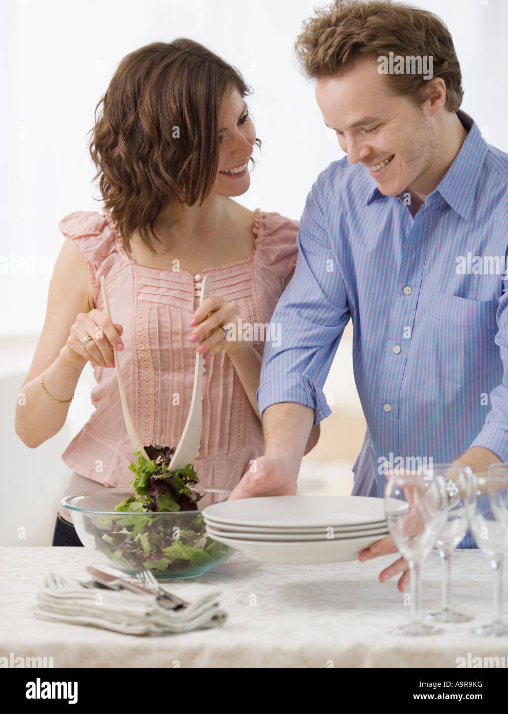 Couple setting table and tossing salad Stock Photo