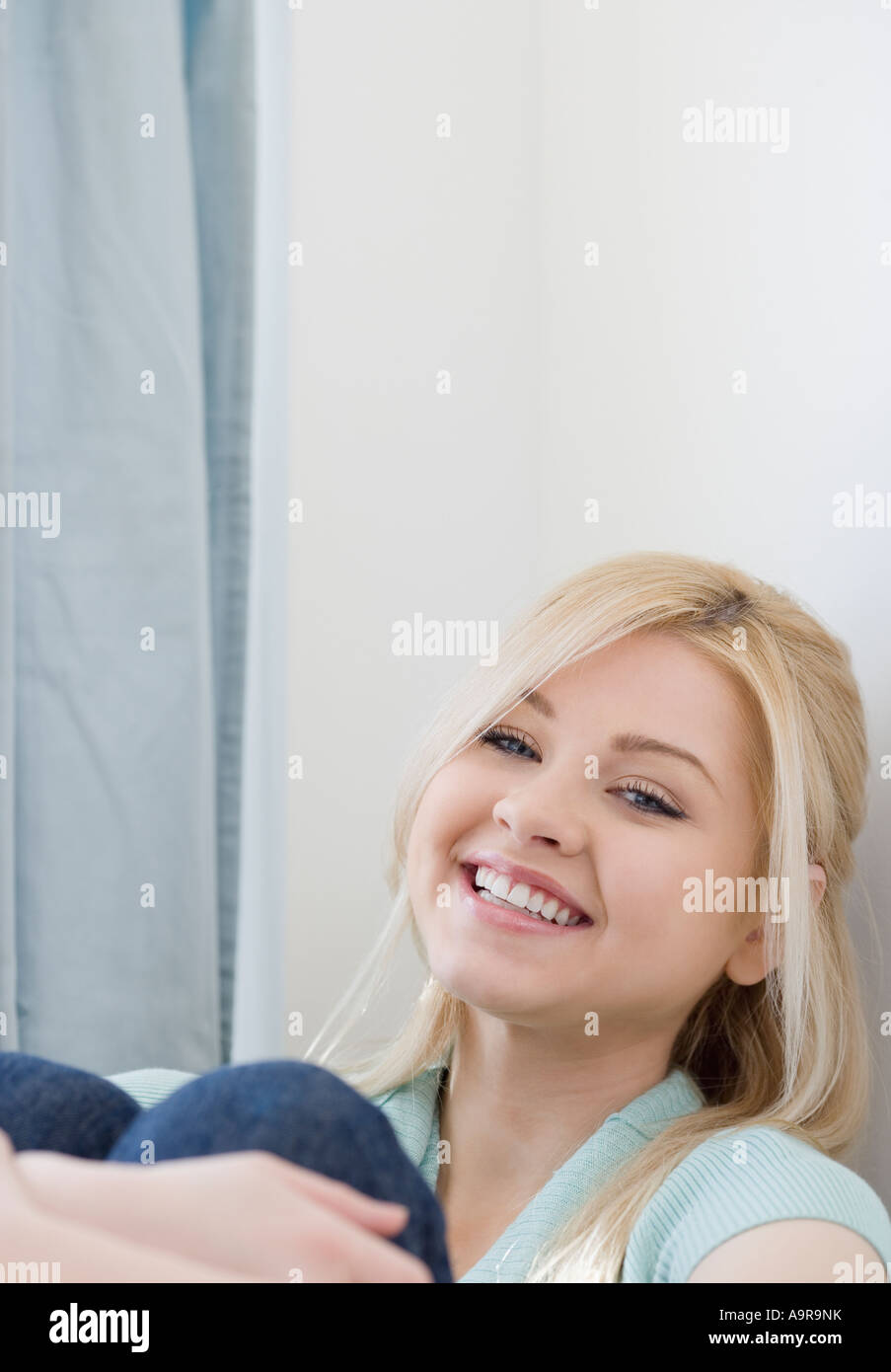 Woman smiling and hugging knees Stock Photo