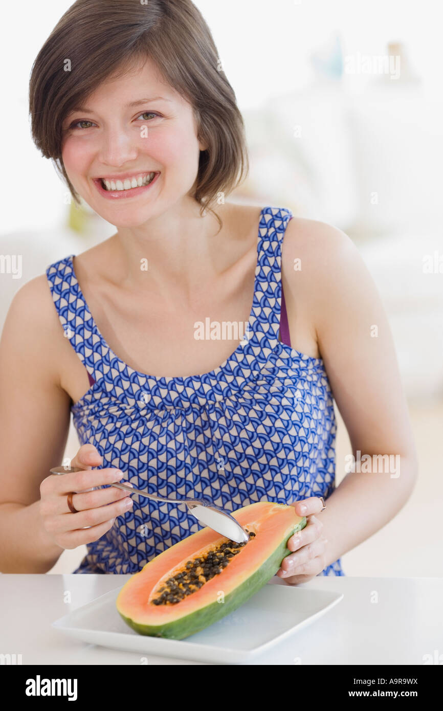Woman eating fruit in kitchen Stock Photo