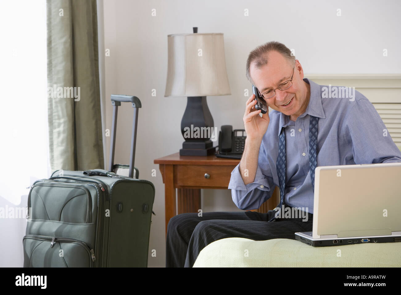 Businessman with suitcase in hotel room Stock Photo