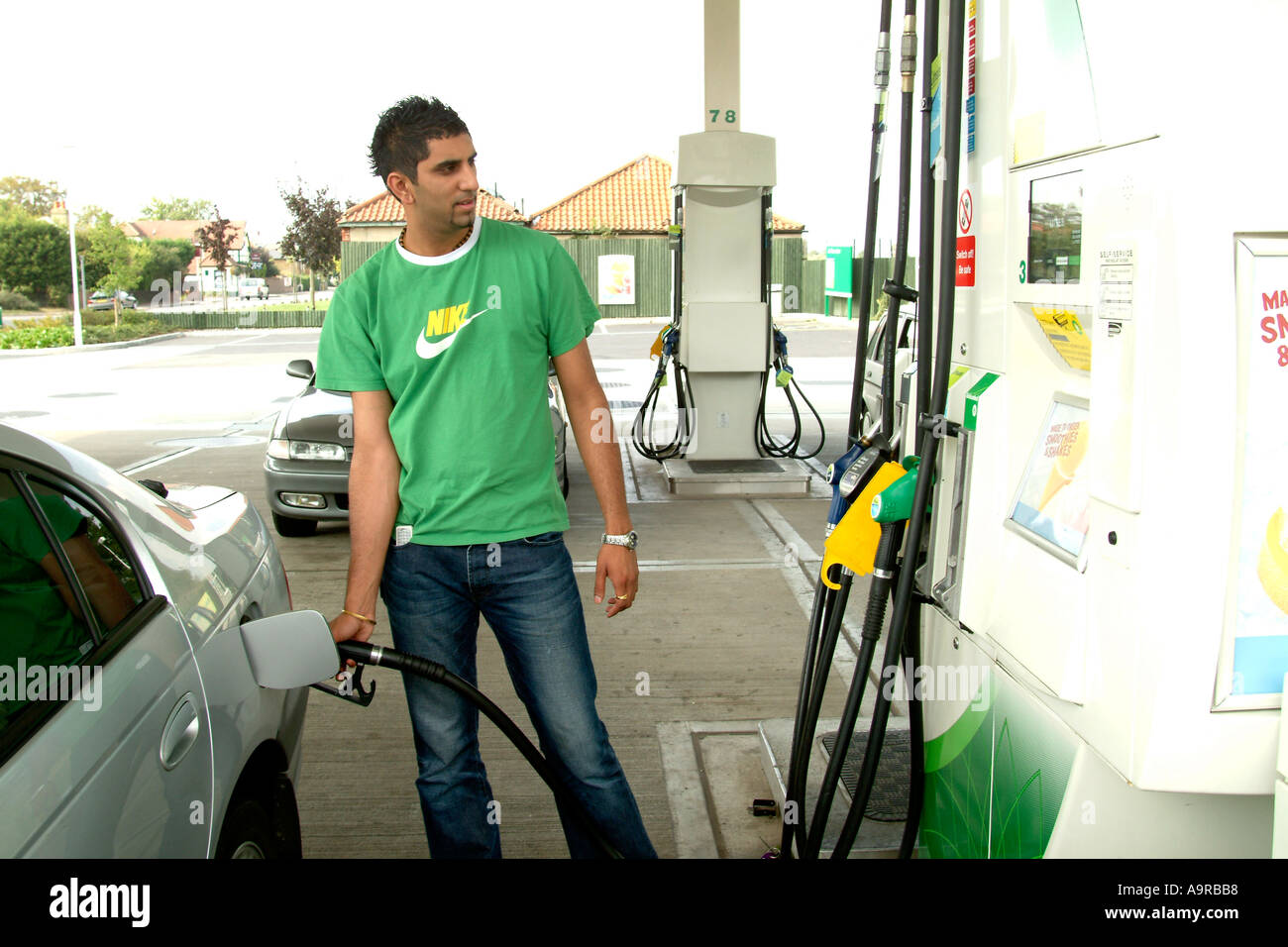 Asian man filling up his car with petrol at a filling station, Hampton, UK. Stock Photo
