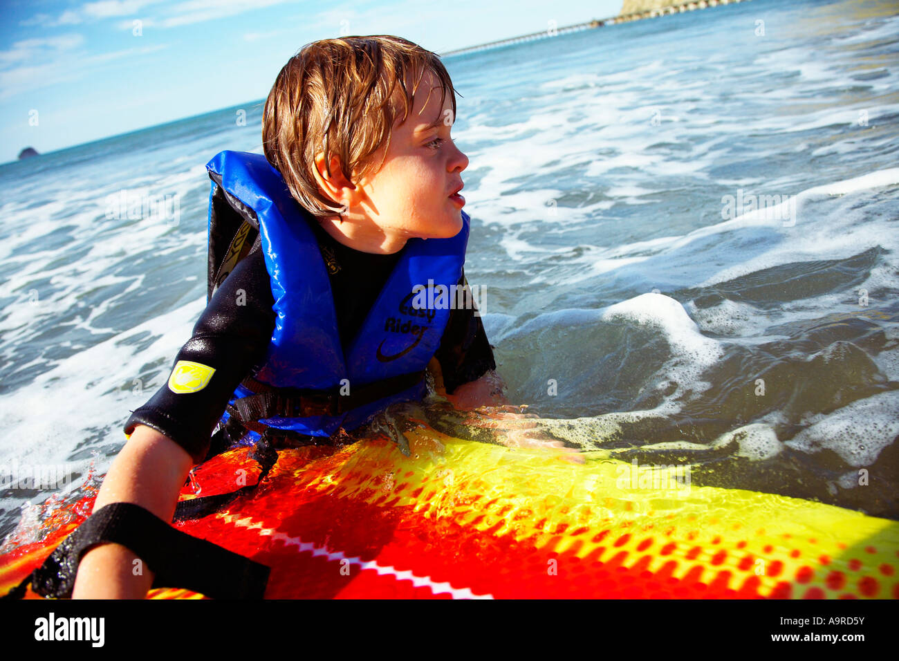boy 6 playing in the surf on body boogie board wearing wet suit and