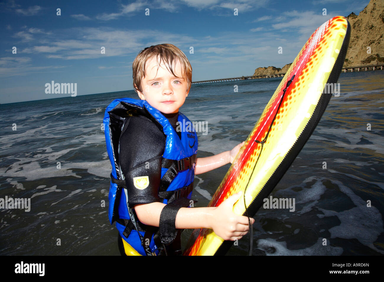 boy 6 playing in the surf on body boogie board wearing wet suit and