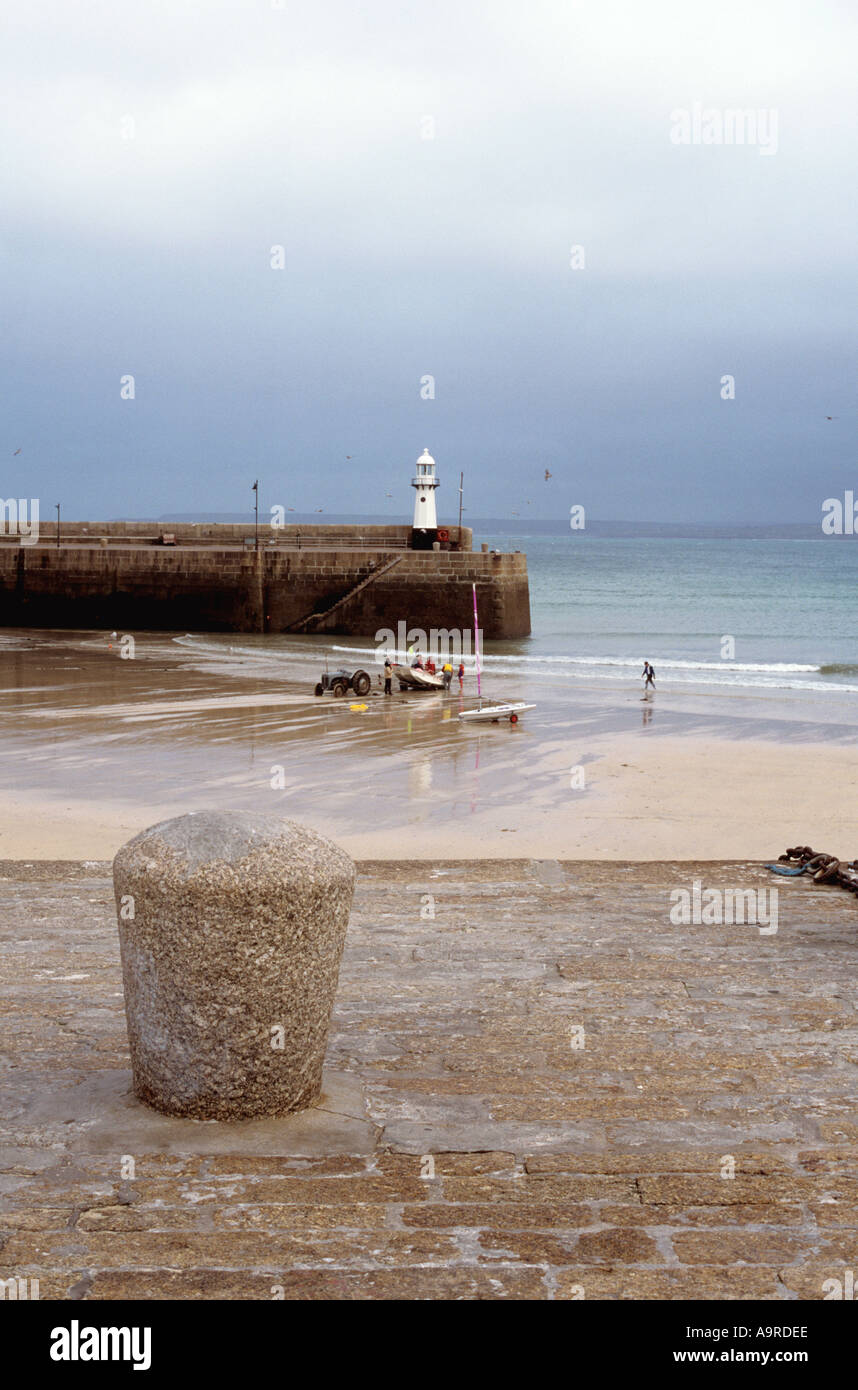 Harbour scene showing Smeatons Pier and the lighthouse at low tide in the fishing town of St Ives in Cornwall in the UK Stock Photo