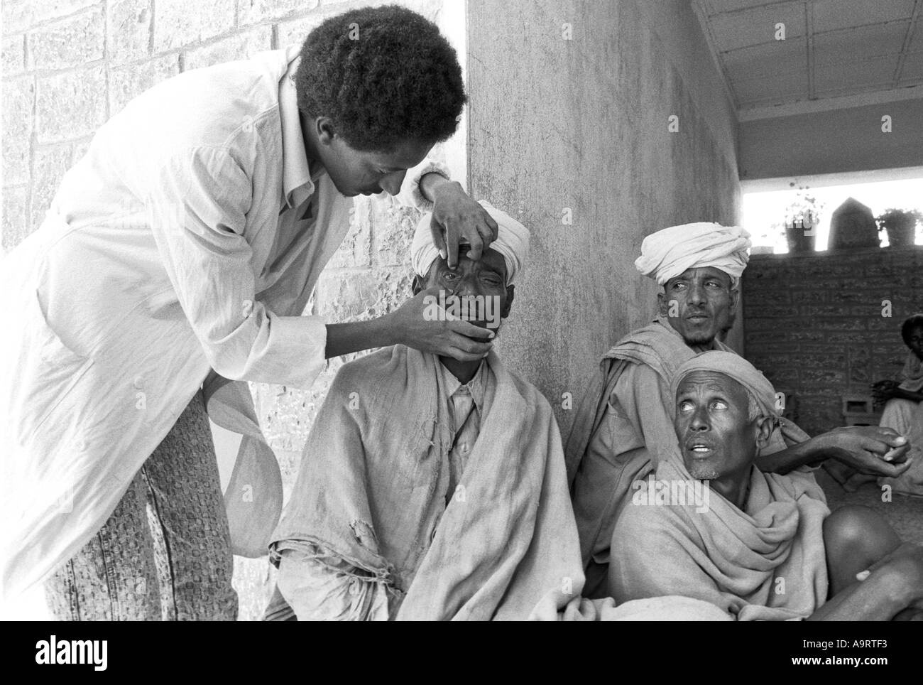 B/W of a doctor examining local men at an eye clinic. Mekelle, Tigray, Ethiopia Stock Photo