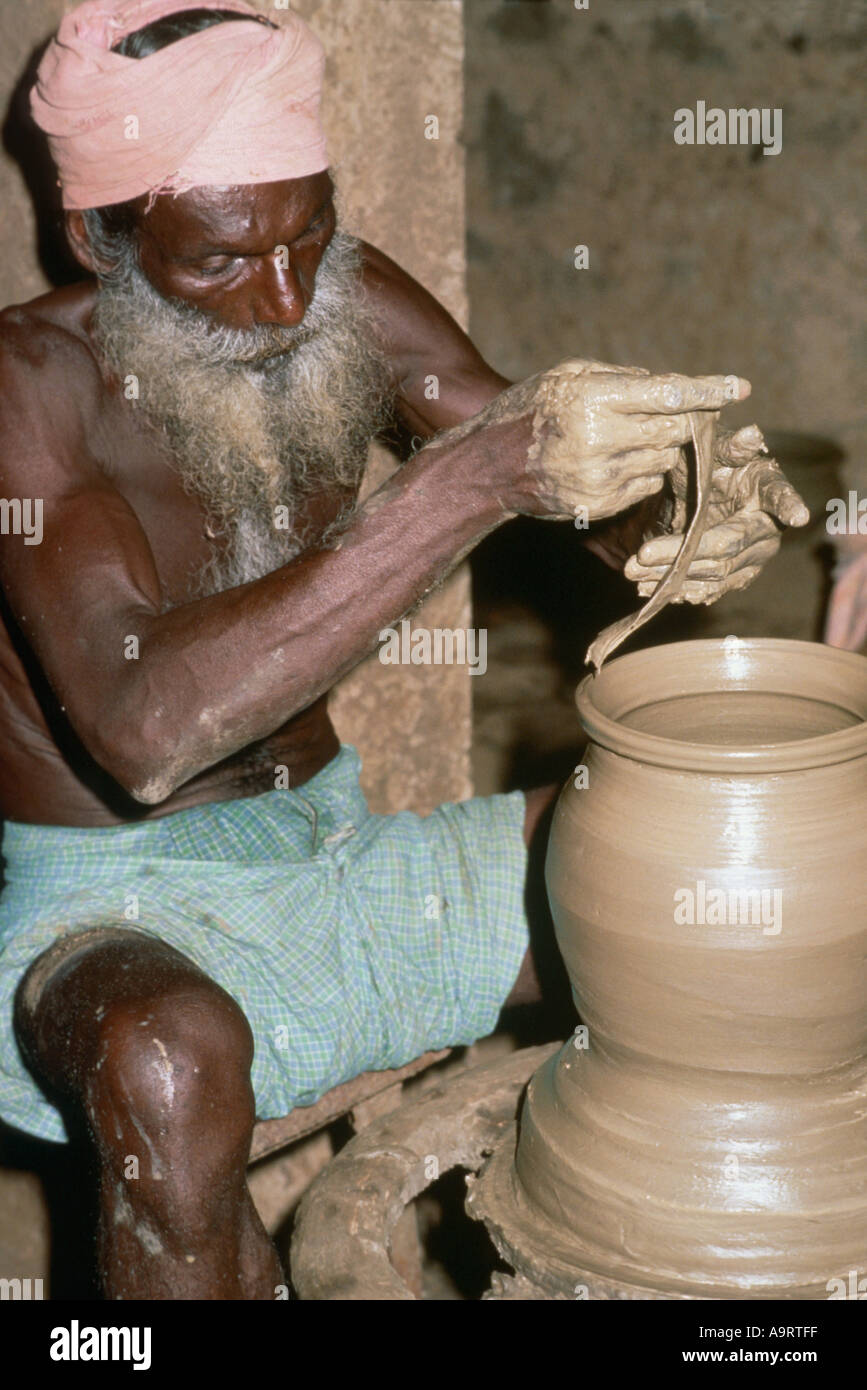Elderly bearded potter turning a pot at a manual potters wheel. Tamil