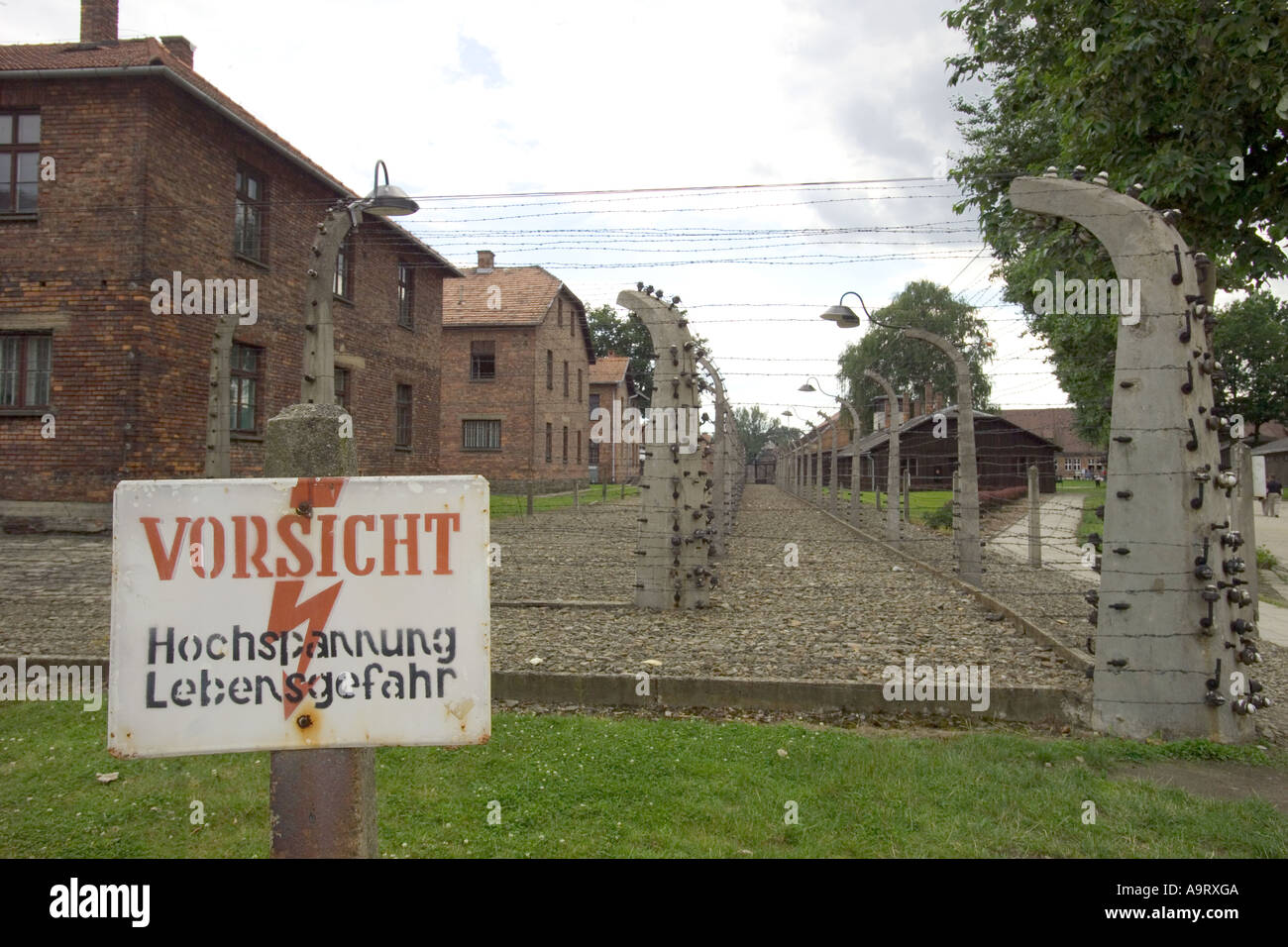 The sign says 'Caution, high voltage, mortal danger' and barbed wire fence at Auschwitz 1 concentration camp in Poland. Stock Photo