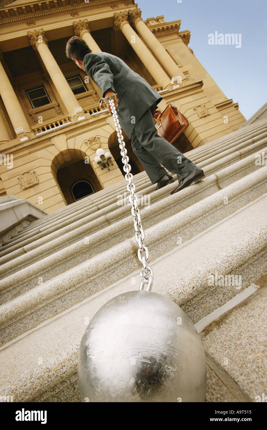 Businessman carrying a ball and chain Stock Photo