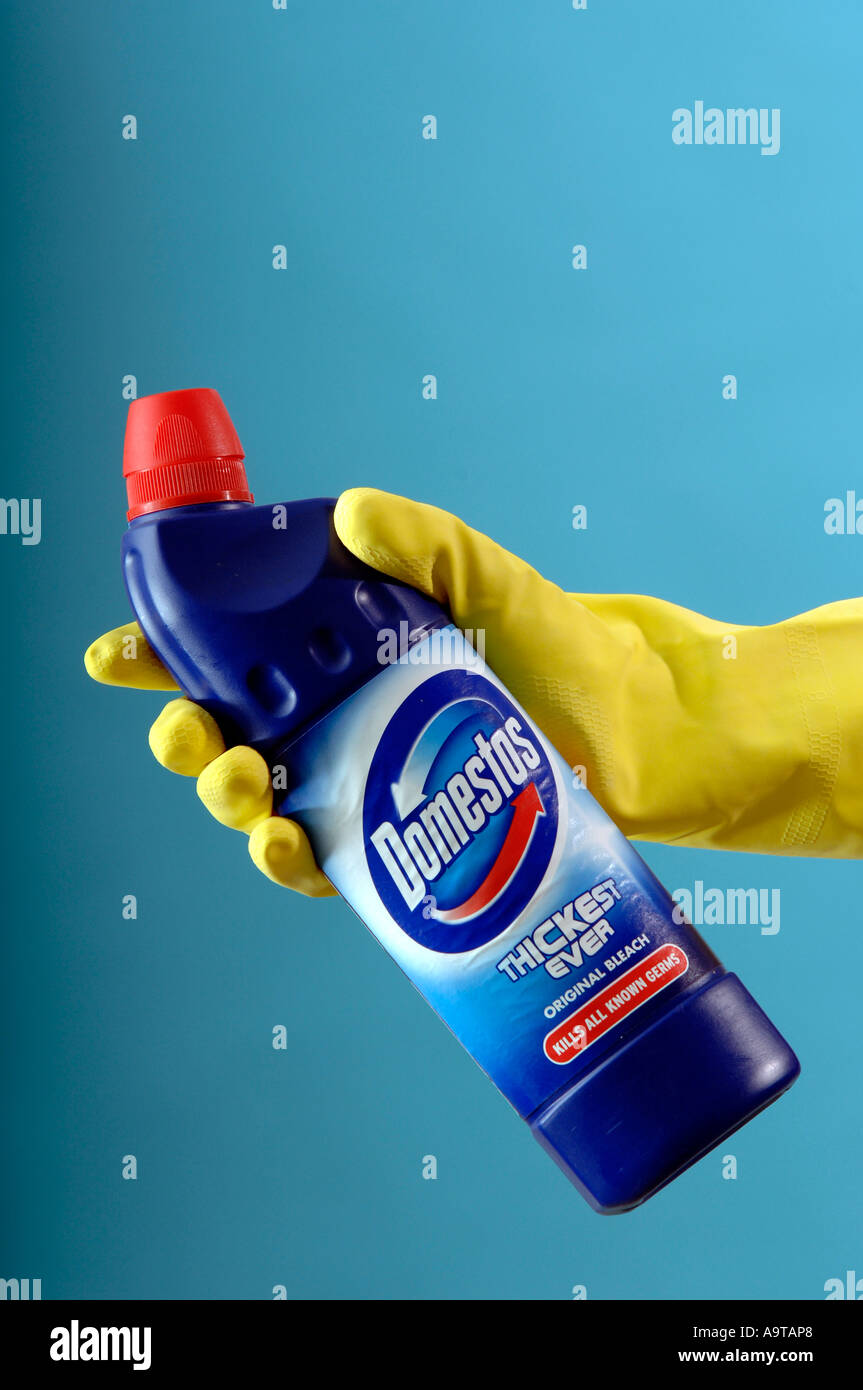 generic of yellow cleaning gloves holding Domestos bleach Stock Photo