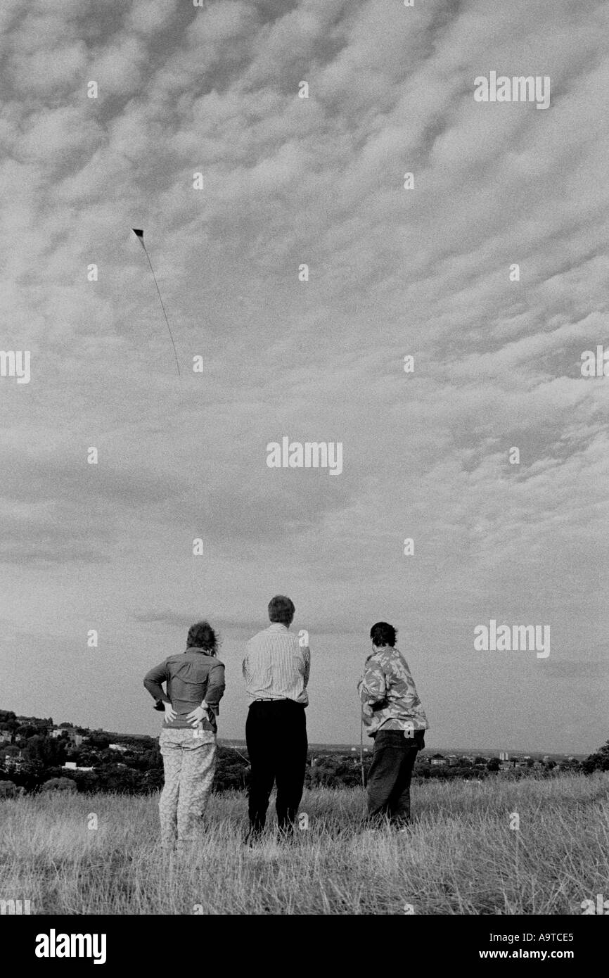 3 people watching kite flying Stock Photo Alamy