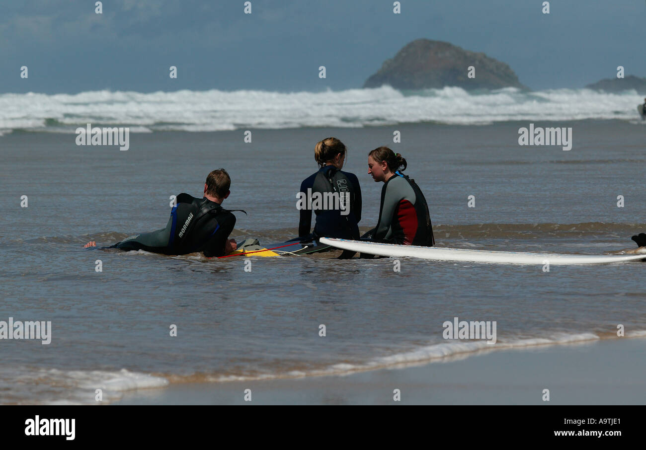 Three surfers stting in sea water chatting and relaxing Stock Photo