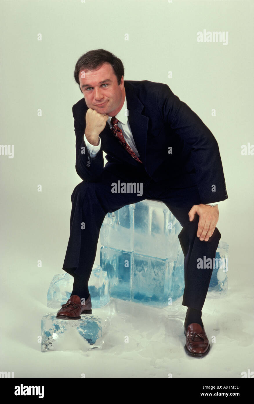 male-executive-sitting-on-block-of-ice-contemplating-copy-space-A9TM5D.jpg
