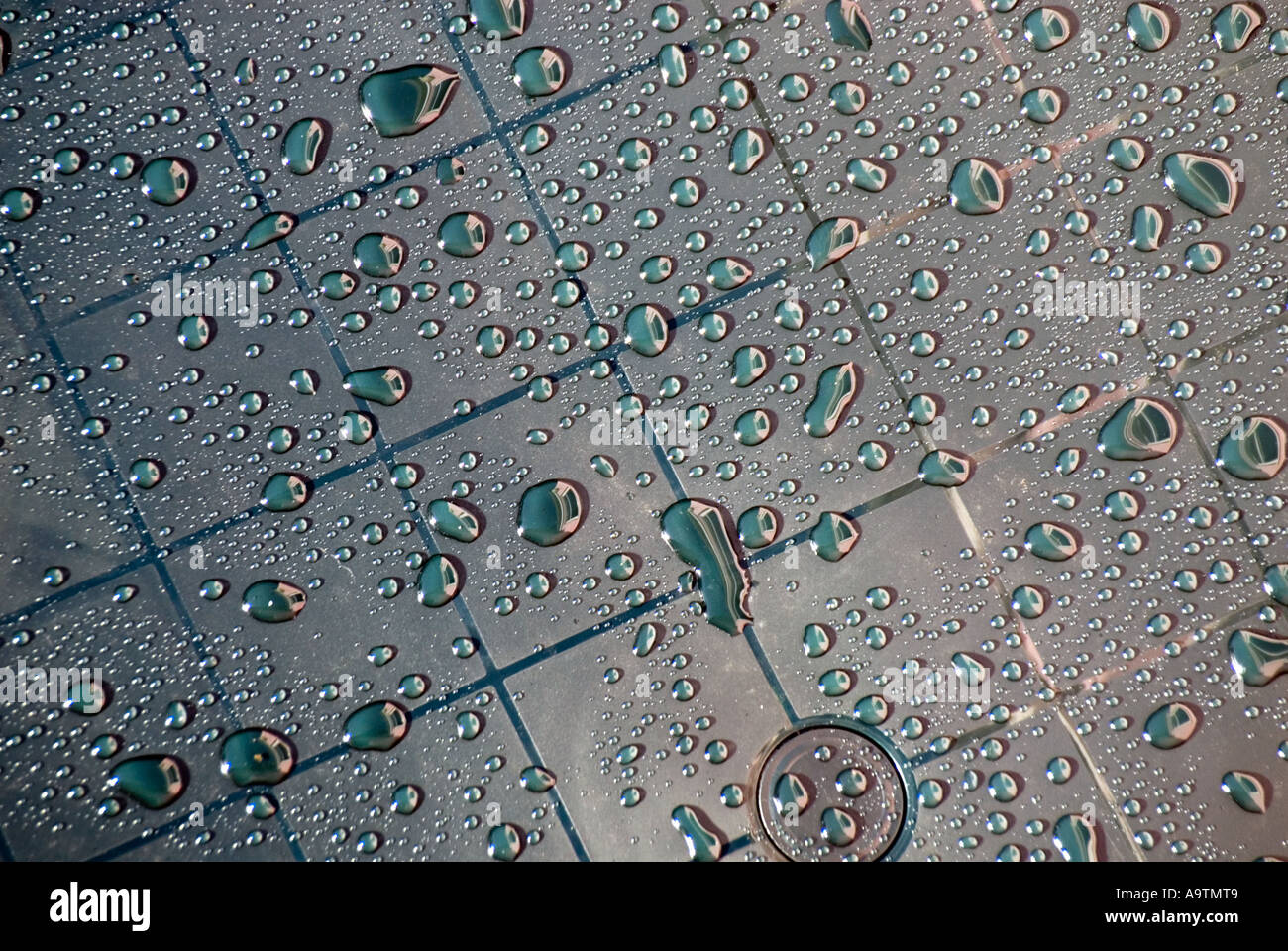 Close up part of abstract arrangement of rainwater droplets on grid marks on new plastic garden table in domestic garden in Essex England UK Stock Photo