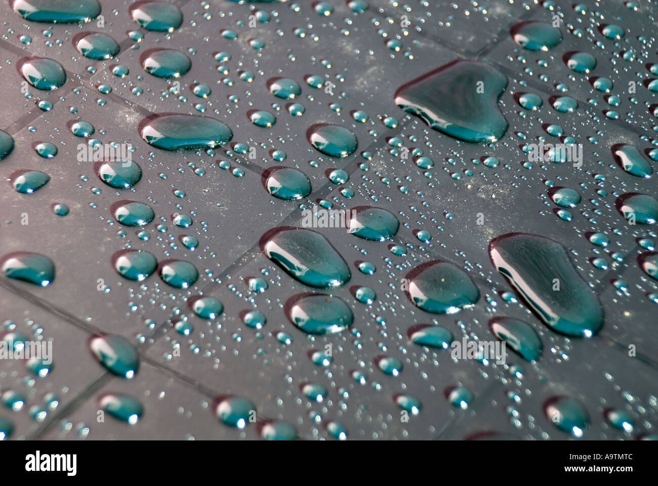Abstract arrangement of rainwater shower creating droplets on grid marks on new plastic garden table outdoors in domestic back garden Essex England UK Stock Photo