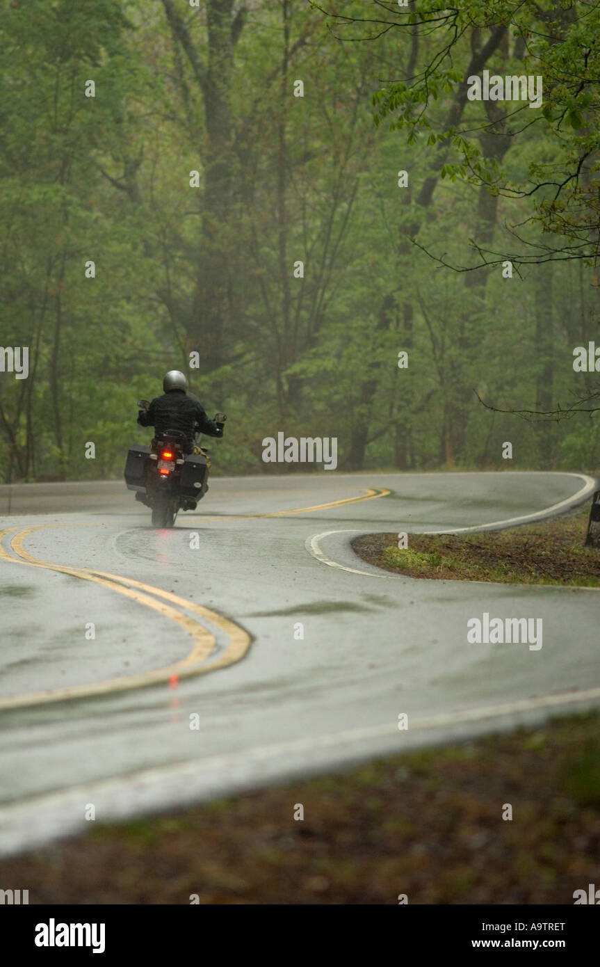 Motorcycle being ridden on a very winding and wet rural road Stock