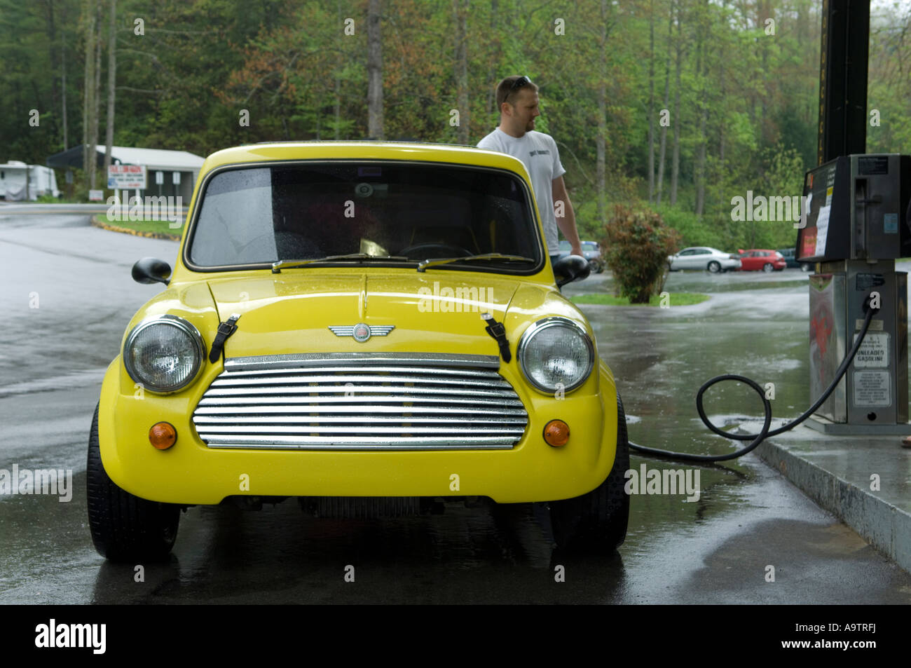 man filling up a classic Mini at a gas station Stock Photo