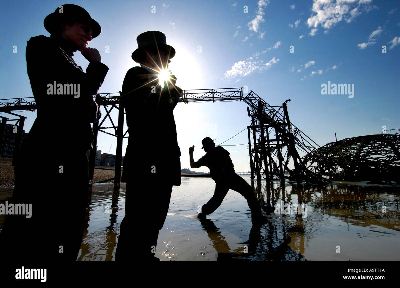 Stone skimming competition on Brighton Beach. A contender lobs a stone, watched by two judges, one in a bowler, one in a top hat Stock Photo